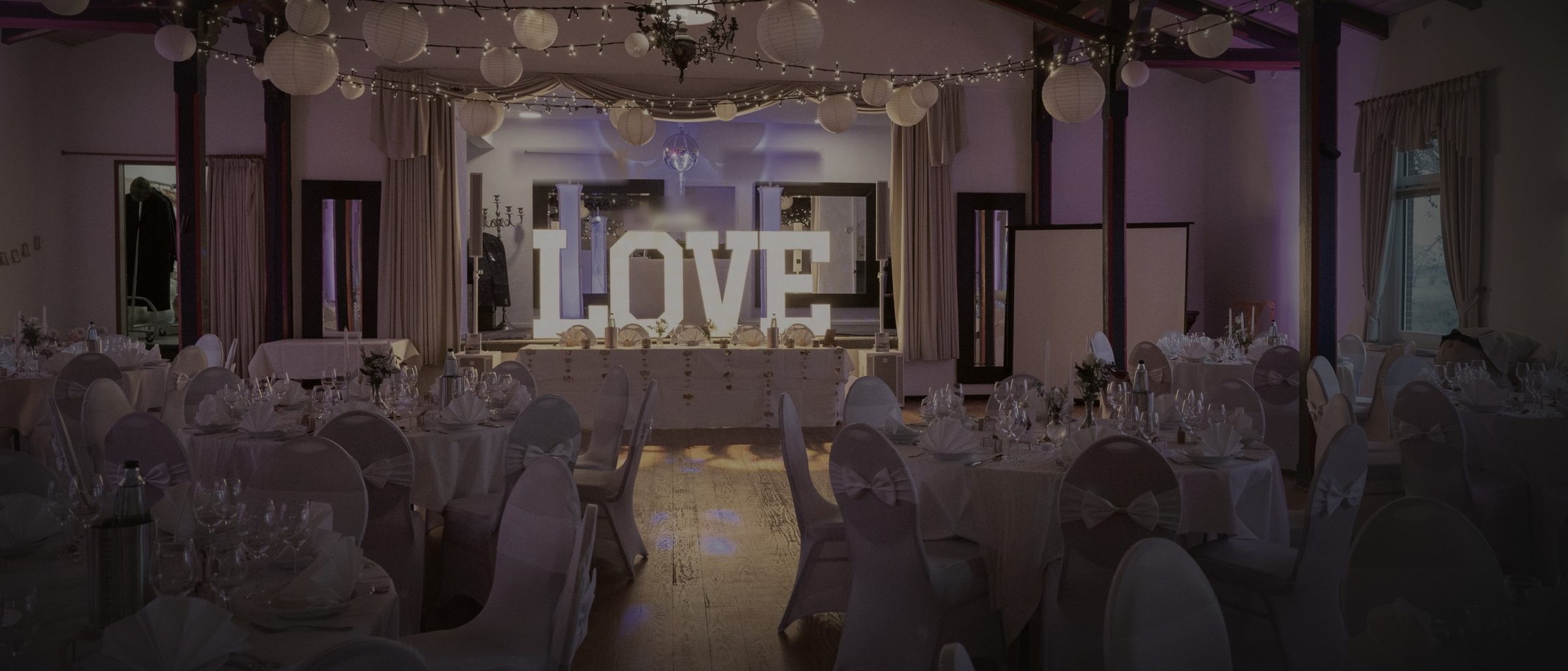 Illuminated LOVE letters in a dimly lit wedding hall